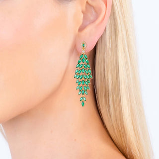 Woman wearing a bright pink earring with a large gold and pink stone earring on a white background