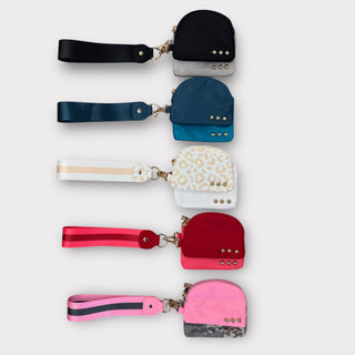 A collection of Dolly Wristlets with multiple styles, featuring various colors and patterns, with zippered pouches and a wrist strap.