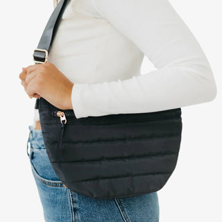 Woman wearing a Pretty Simple Jolie Puffer Belt Bag in black quilted nylon with gold zipper, styled with a white top and denim jeans.