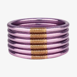 A stacked set of 5 lilac bangles with a gold charm in the center of each bangle
