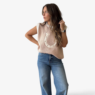 Woman wearing a sleeveless sweater vest with cream horseshoe detailing