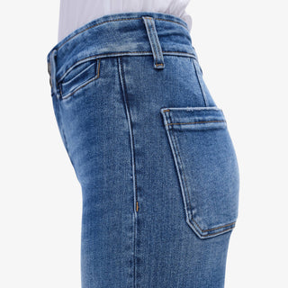 Woman wearing High Rise Wide Leg Jeans in medium wash denim with cropped raw hem, styled with white blouse and heels.