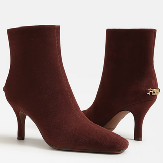 Pair of brown ankle boots with a gold buckle on a white background