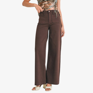 Woman wearing dark brown wide leg jeans with mini patch pockets on a white background