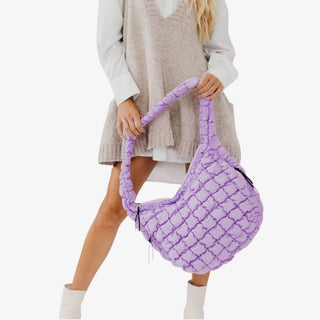 Lavender woven puffer shoulder bag with braided handle worn with neutral sweater vest outfit.