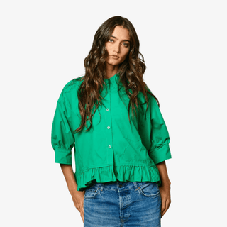 Emerald green button front blouse with puff sleeves and ruffle hem styled with medium wash denim jeans. 