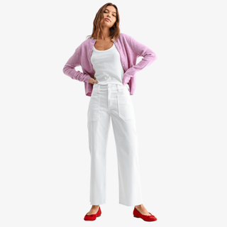 Model wearing a pink button-front cardigan layered over a white tank top with high-rise white wide-leg cropped pants and red ballet flats against a light gray background.