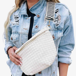 Close-up of a woman wearing a cream woven Pretty Simple Westlyn Bum Bag with a striped adjustable strap over a distressed light denim jacket
