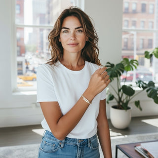 Woman wearing a white t-shirt and blue jeans with a wrap gold and cz diamond bracelet.