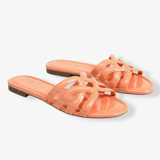 Pair of orange colored slide sandals by Circus by Sam Edelman on a light gray background