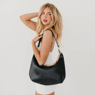 Woman in white dress carrying the Pretty Simple Sienna Woven Bag in black