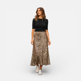 Woman wearing a black top and leopard print skirt on a white background