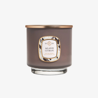 A grey glass jar candle with a gold lid, labeled 'Agave Citron' with a white and black patterned label.
