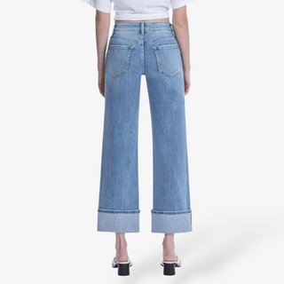 Person wearing light blue wide-leg jeans on a white background