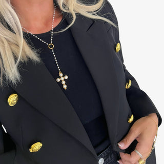 Lady wearing a black blazer with pearl necklace and cross drop