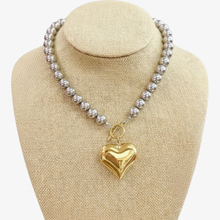 Necklace with a gold heart pendant on a beige bust