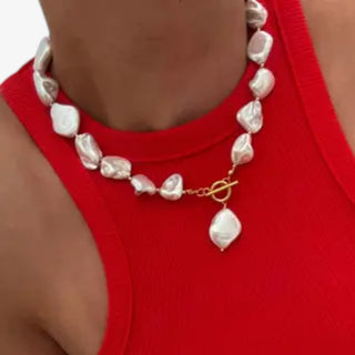 Chunky baroque pearl necklace with oversized ivory freshwater pearls and gold toggle clasp worn with red sleeveless top