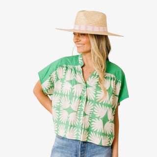 Sunshine Tienda green floral print top with cap sleeves and relaxed fit styled with denim and straw hat front view