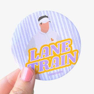3-inch Lane Train game day button featuring a coach in white with purple and gold lettering on a lavender striped background, front view