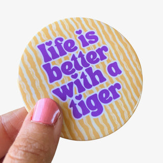 3-inch Life Is Better with a Tiger game day button with purple lettering on a gold tiger stripe background, front view
