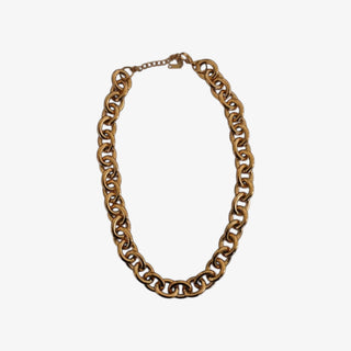 Chunky gold chain necklace with bold interlocking links on marble background
