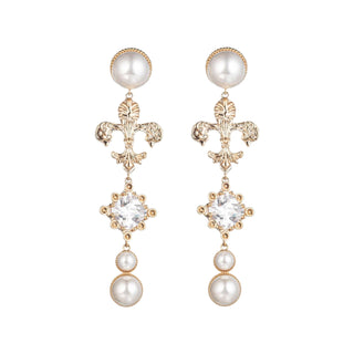 Woman wearing gold Fleur de Lis drop earrings with pearl accents and crystal center, elegant Southern-inspired jewelry
