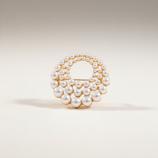 Pearl brooch in a gold setting on a light grey background