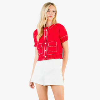 Contrast stitch knit button up top with short sleeves, decorative buttons, and tailored pockets in red or white