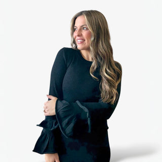 Woman wearing a black set with ruffled sleeves against a white background