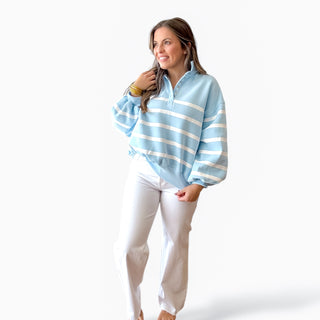 Woman wearing felicity blue and white stripe sweatshirt, with white wide leg jeans on a white background 