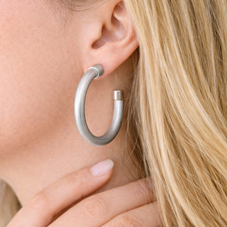 Brushed Silver hoop earring medium size worn by a woman with blonde hair.