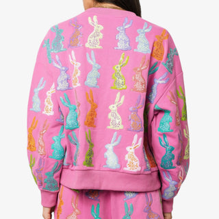 Pink sweatshirt with sequin rabbits worn by a woman on a white background