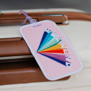 Pink embroidered Weekend luggage tag with rainbow lettering and white trim