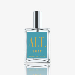 Clear glass perfume bottle with silver cap labeled “ALT. Lust Extrait de Parfum” on a teal and yellow label against a white background 
