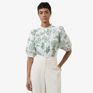 White blouse with green floral print, smocked neckline and puff sleeves styled with cream high waisted trousers