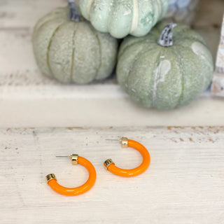 Light Orange hoop earrings on a wooden surface with pumpkins in the background