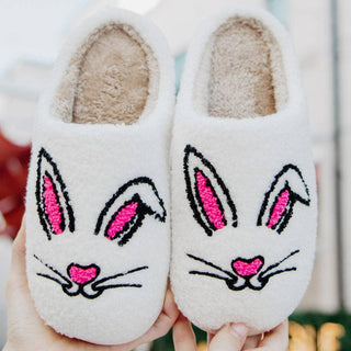 White bunny face plush slippers with embroidered pink ears and nose, cozy faux fur lining, and slip-on design perfect for Easter lounging