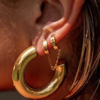 Double gold hoop earrings linked with a chain on ear