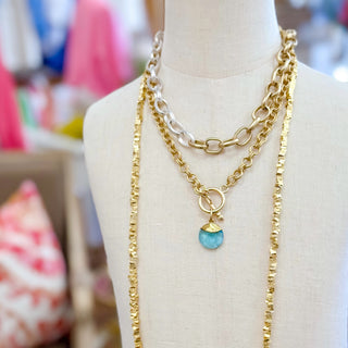 Aquamarine blue gemstone gold filled pendant necklace layered with chain necklaces on mannequin