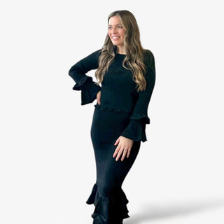 Woman wearing a black outfit with ruffled details on a white background