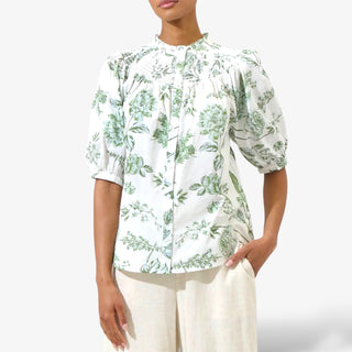 Woman wearing a white blouse with green floral pattern on a white background