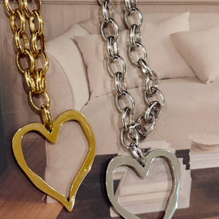 Open heart necklace in 18K gold plated finish with adjustable chain worn layered on model