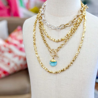 Aquamarine gemstone gold filled pendant necklace layered with chain necklaces on mannequin
