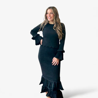 Woman wearing a black dress with ruffled details on a white background