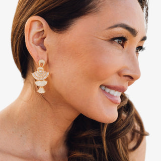 Gold crystal tiered statement dangle earrings with baguette and pave stones worn on model