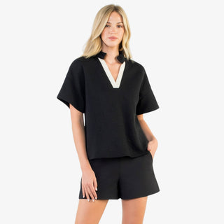 Woman wearing black contrast trim v-neck top with short wide sleeves
