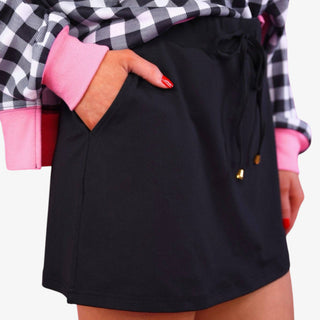 Women's black performance skort with side pockets, adjustable drawstring waist and gold-tone tips, shown in a front detail view.
