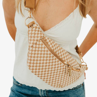 Tan and cream checkered belt bag with woven texture, gold-tone zippers, and adjustable strap worn crossbody, front lifestyle view.