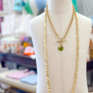 Green gemstone gold filled pendant necklace with toggle clasp layered with chain necklaces on mannequin