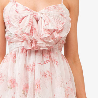 Pink floral tiered midi dress with bow detail bodice and ruffle layers styled with white heels